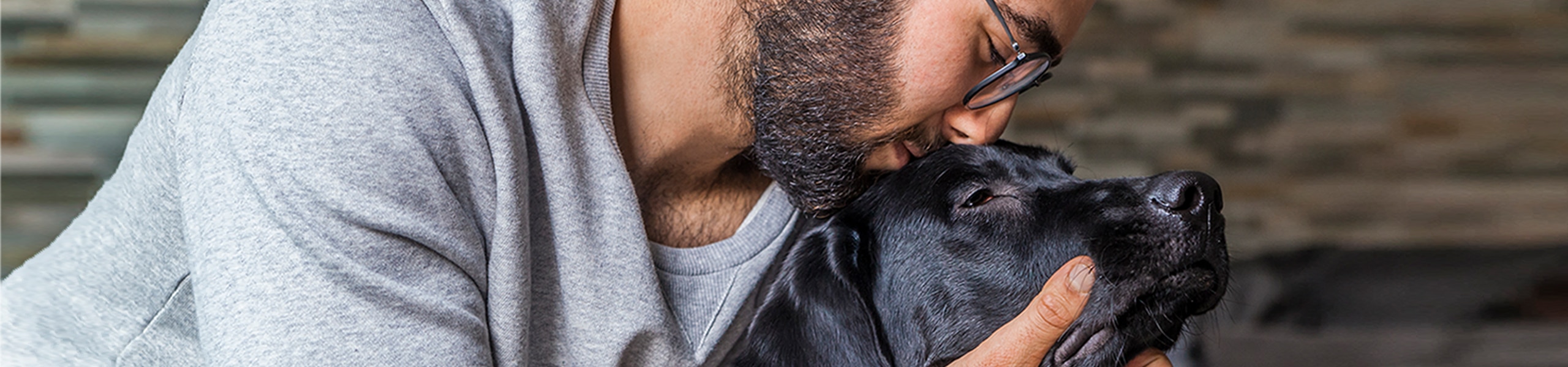 Una persona sonriendo mientras abraza a un perro