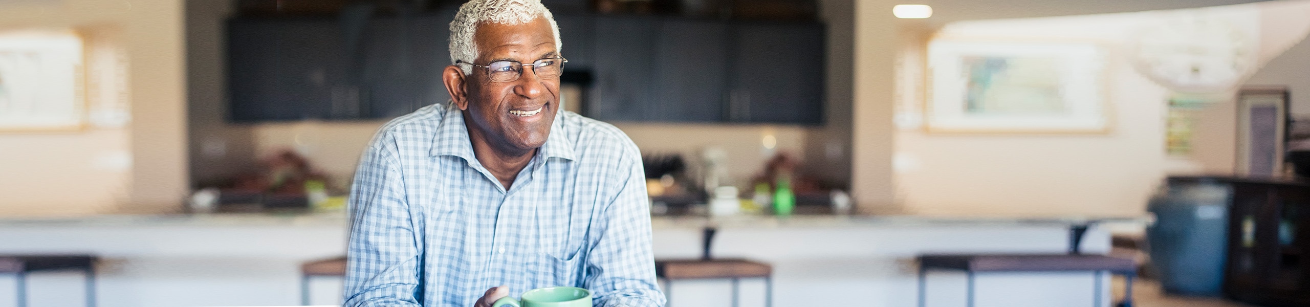 Un hombre de edad avanzada sostiene una taza de café.