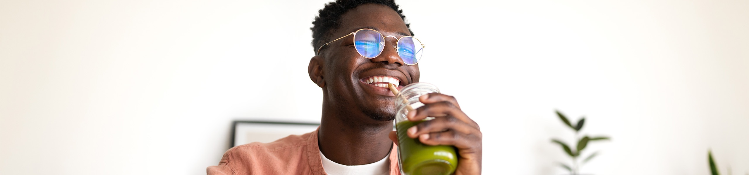 Persona feliz que bebe un jugo de color verde