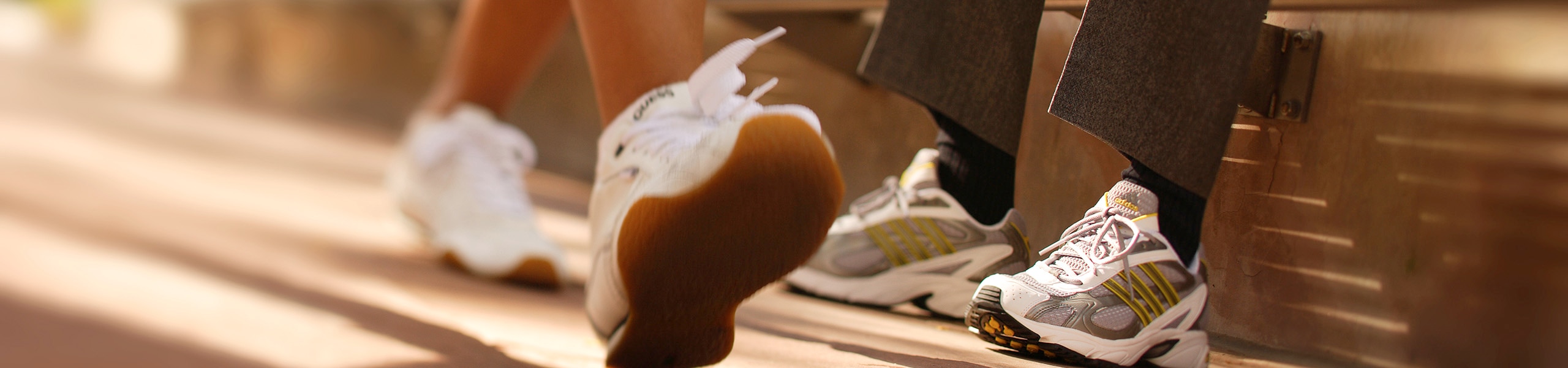 Persona con calzado deportivo que camina frente a una persona sentada