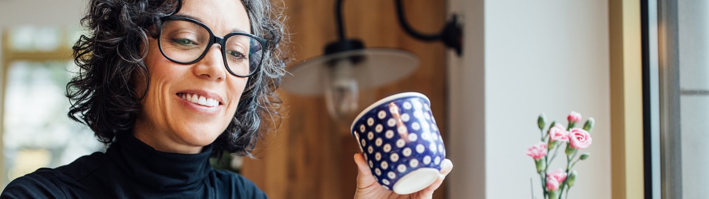Persona sonriendo mientras sostiene una taza de café