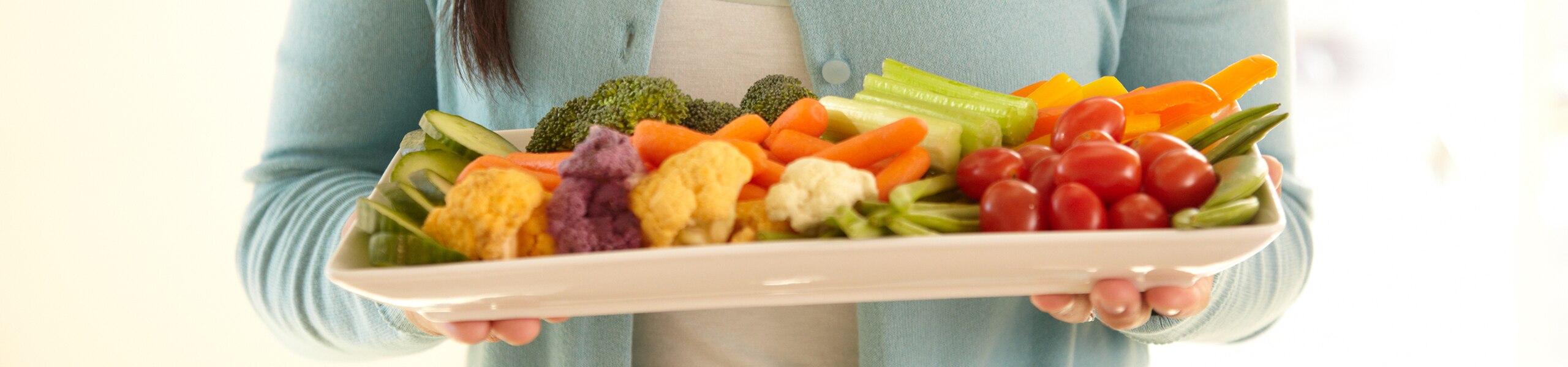 Una persona sosteniendo un plato con verduras crudas variadas