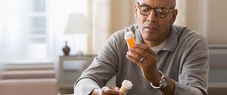 Hombre que lee la etiqueta de un frasco de medicamento