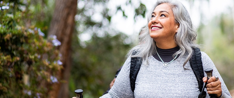 Mujer sonriente que mira hacia arriba mientras hace senderismo