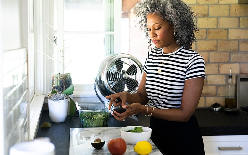 Mujer que prepara una ensalada en la cocina