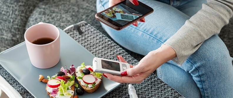 Mujer que toma una foto de la comida y de la lectura del glucómetro