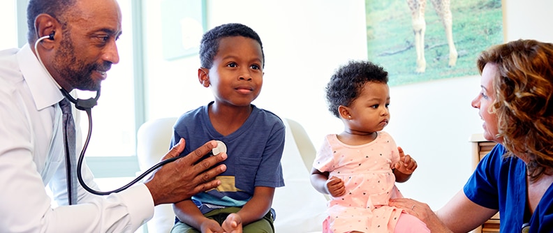 Una niña y un niño pequeños durante los exámenes con el médico y la enfermera.