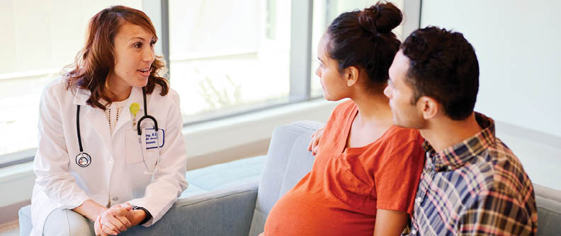 Pareja de futuros padres en una consulta con una médica en la sala de espera.