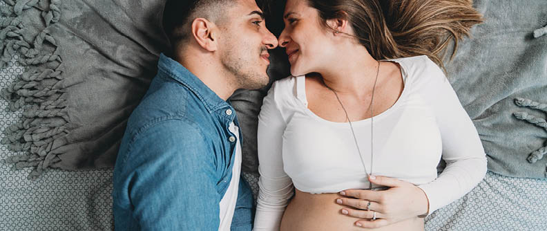 Pareja de mileniales en la dulce espera acostados juntos en la cama.