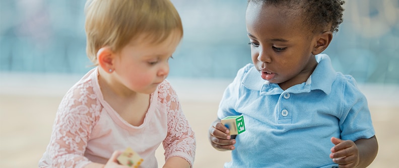 Dos niños pequeños jugando con bloques de letras en una guardería infantil.