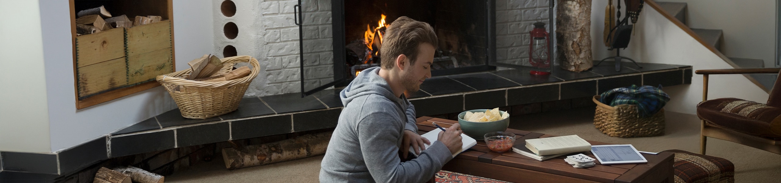 Persona escribiendo en un diario junto a una chimenea