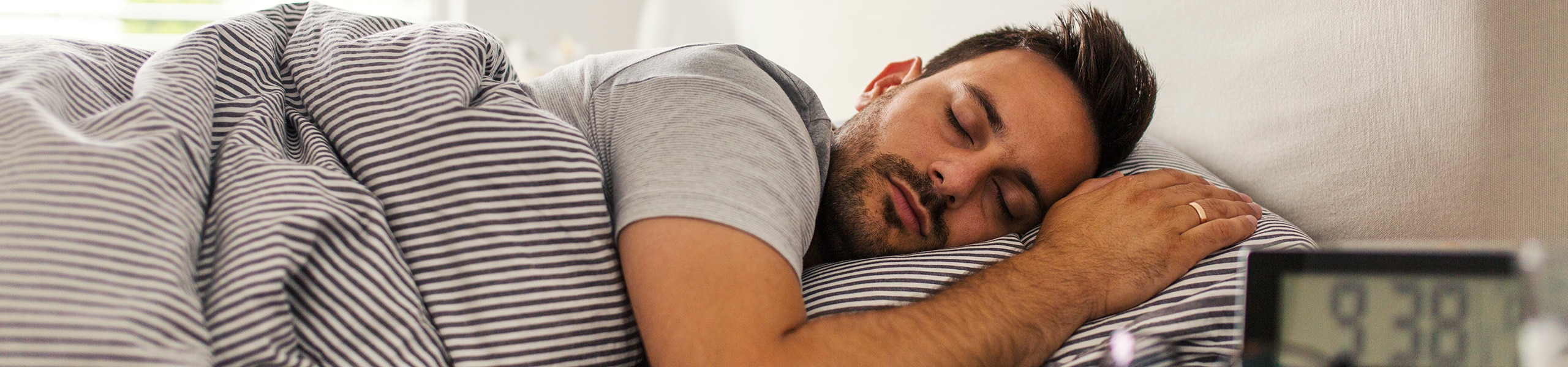 Hombre durmiendo de costado con la cabeza descansando en una almohada 