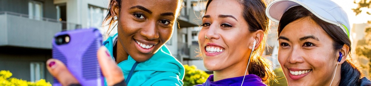 Three smiling friends take a selfie on a mobile phone 