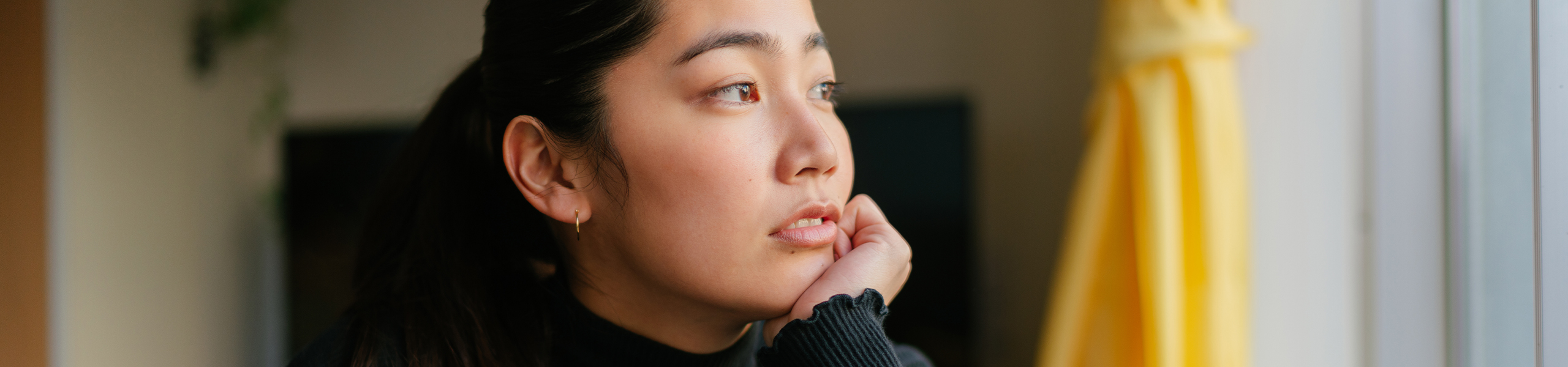 Mujer joven mirando por una ventana y contemplando 