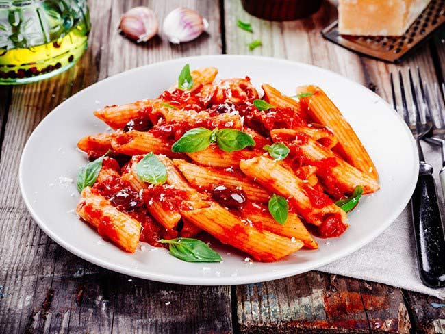 Whole-wheat pasta with red lentil roasted pepper marinara sauce garnished with basil and cheese