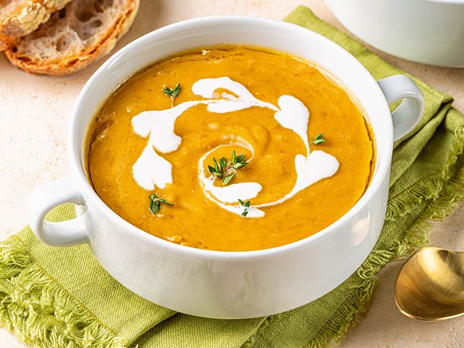 Vegan curried squash lentil soup with vegetable cream and thyme.