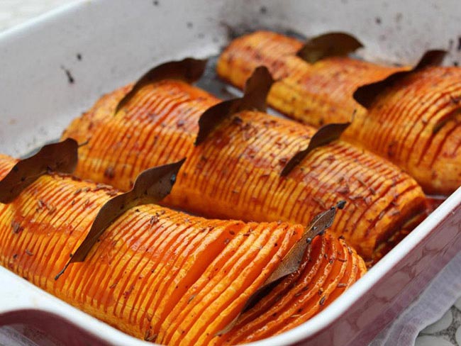 Thinly sliced squash with bay leaves served on a white tray 
