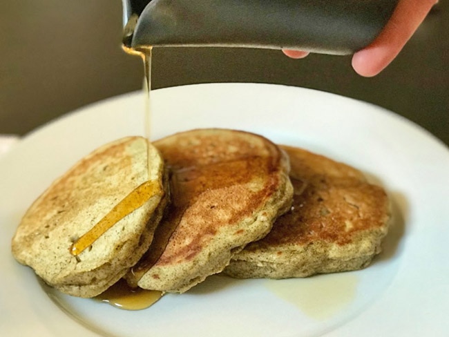 3 squash and maple buttermilk pancakes with maple syrup being drizzled on them