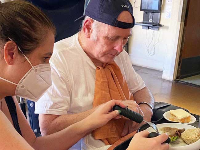 A woman helping her senior-aged father eat a meal.