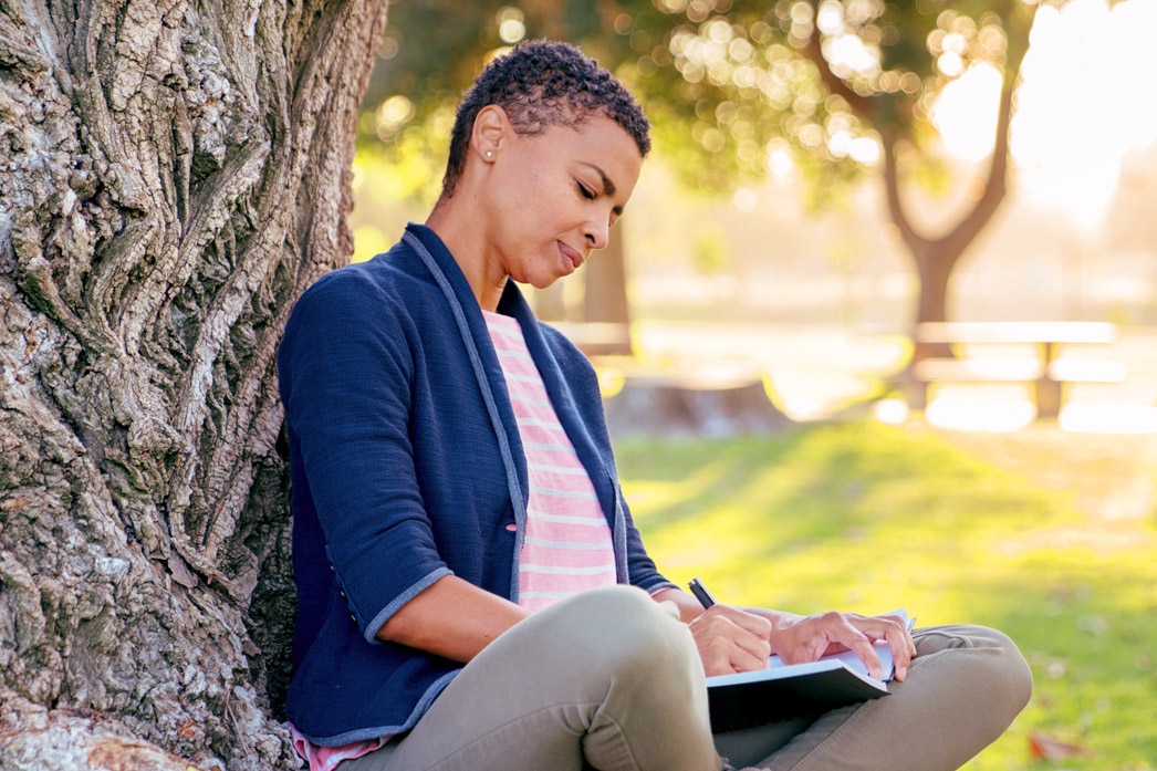 Persona escribiendo en un diario en un parque