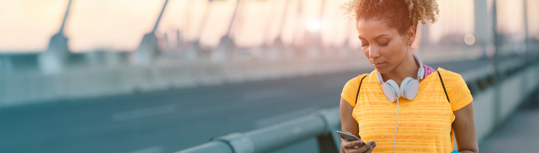 Corredora deteniéndose en un puente para mirar su teléfono
