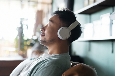 Persona joven usando auriculares con los ojos cerrados