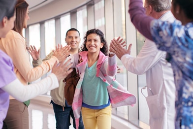 Niña saliendo del hospital y chocando los cinco con el personal