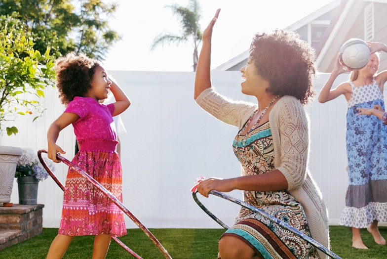 Madre e hija jugando con aros de hula hula en el patio