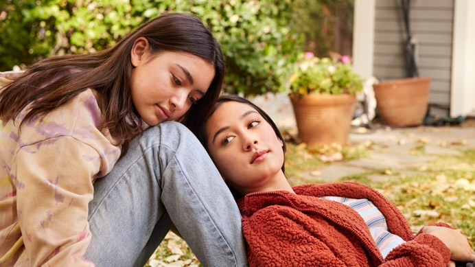 2 personas jóvenes sentadas juntas sobre el césped
