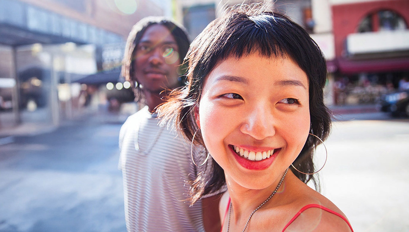 Two people smiling and walking in a city