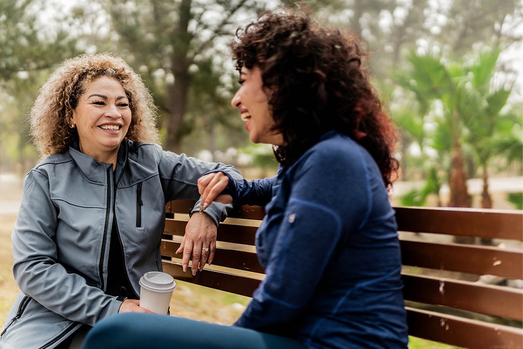 Amigas riéndose en el banco de un parque