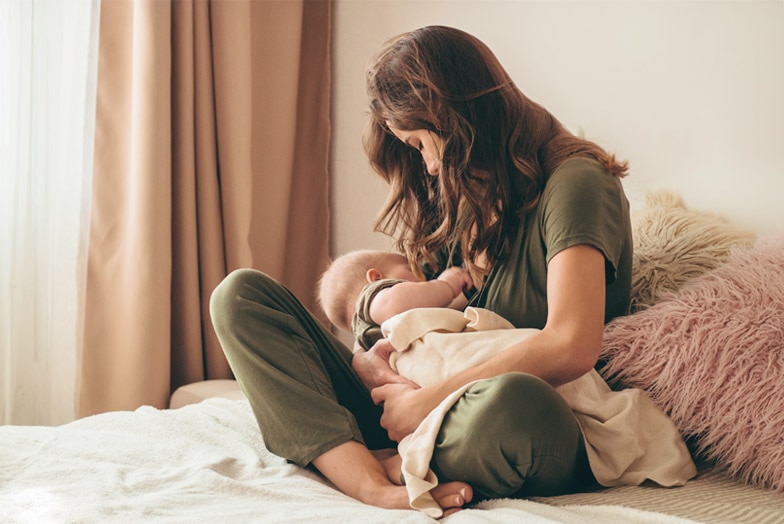 Madre amamantando a su bebé en la cama