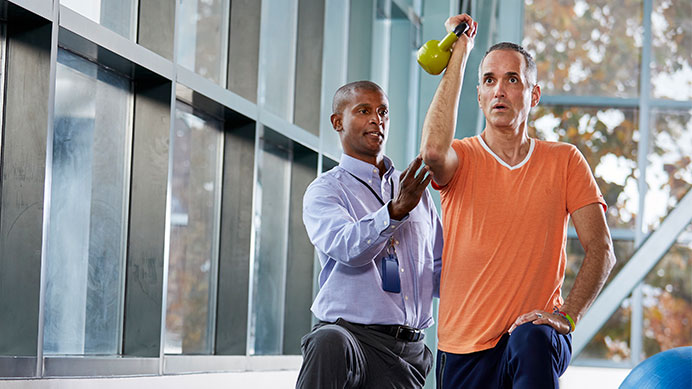 Person doing kettlebell exercise with an athletic trainer