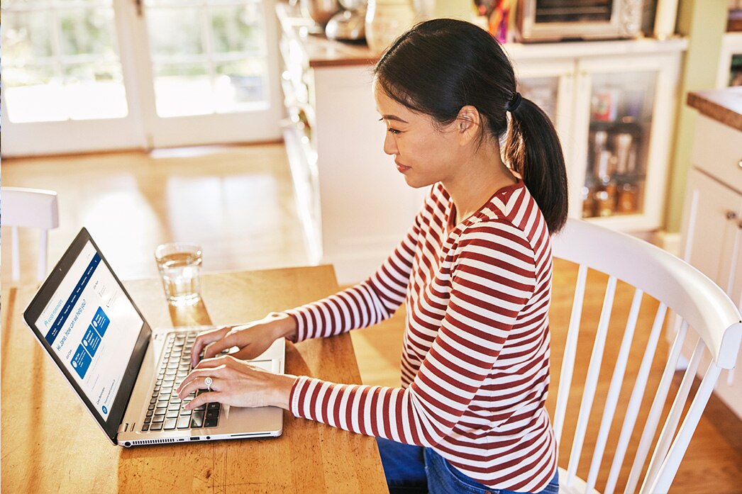 Person viewing health account on a laptop at the kitchen table