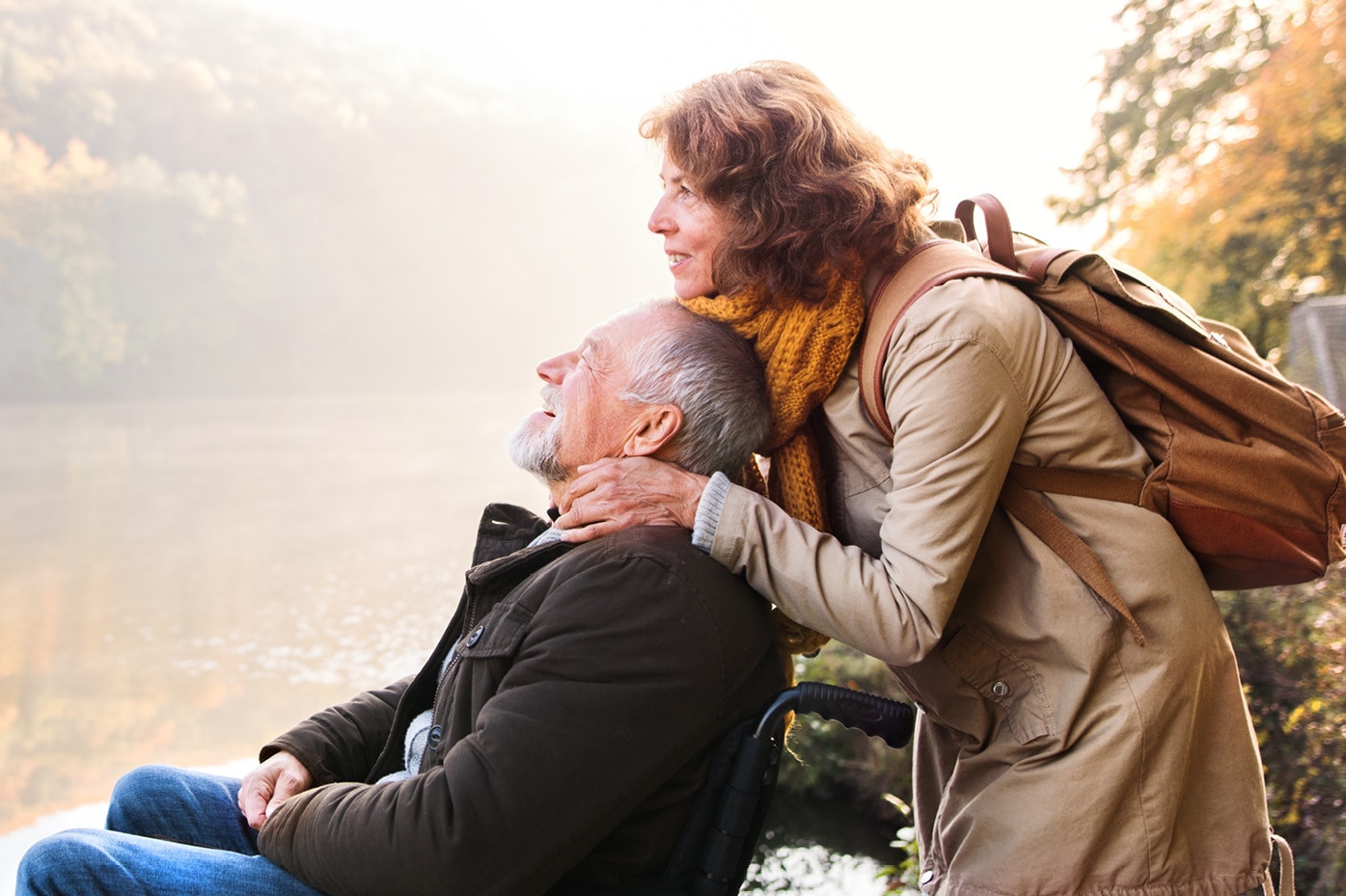 Dos personas apoyándose la una en la otra y disfrutando la vista de un lago