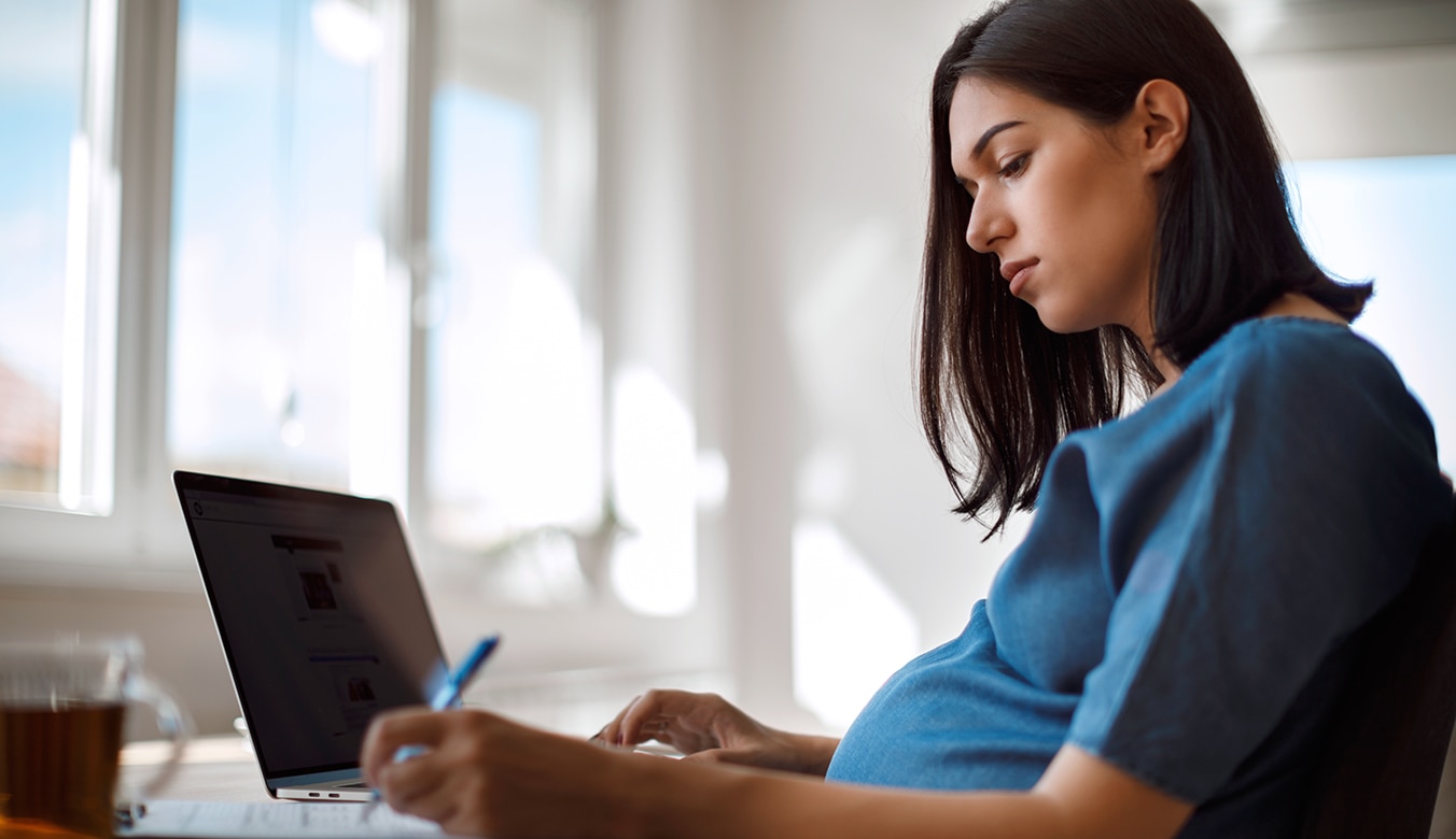 Pregnant person working at laptop