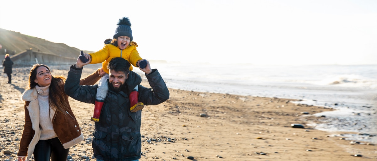 Personas con su hijo caminando por un mirador frente al océano