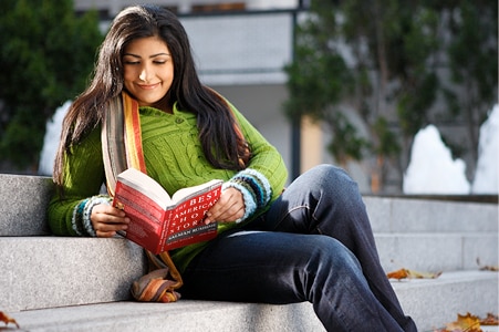 Estudiante leyendo un libro sobre unos escalones