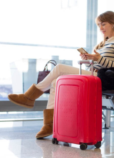 Persona que se va de viaje con una maleta roja esperando en el aeropuerto