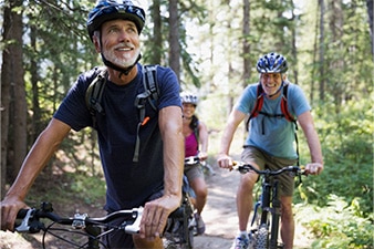 Tres amigos que andan en bicicleta por un camino en el bosque