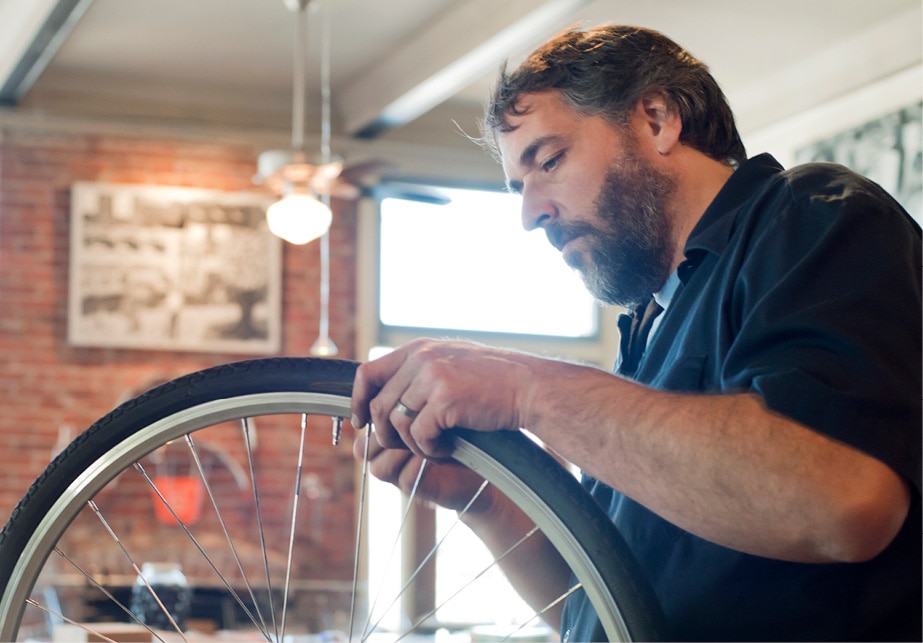 Una persona con barba reparando el neumático de una bicicleta