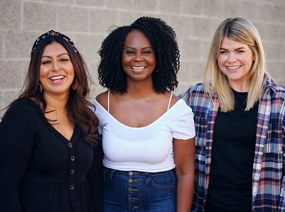 Three teachers sit at table in a library and review a document together. 