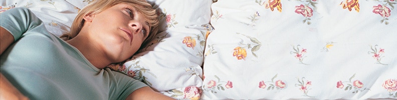 young woman lying awake in bed