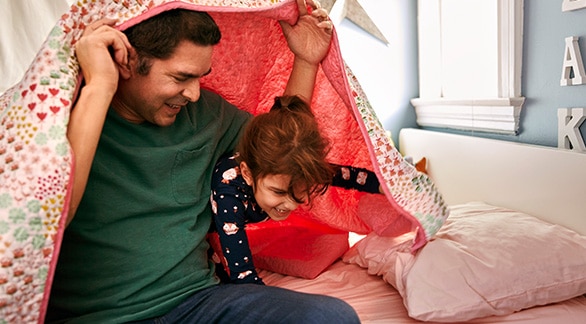 Padre e hija jugando debajo de una manta