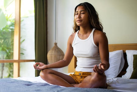 Persona meditando en la cama