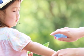 Adulto aplicando protector solar en el brazo de un niño