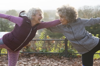 Adultos sonrientes con ropa deportiva haciendo ejercicios de estiramiento al aire libre