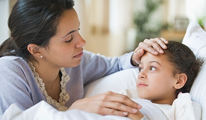 Persona que apoya la mano sobre la frente de su hijo enfermo