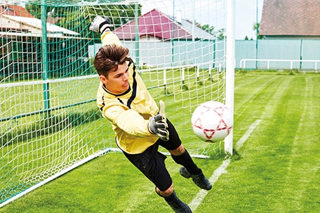 Portero saltando para detener una pelota de fútbol