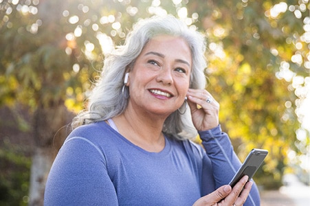 Persona sonriendo y usando sus auriculares al aire libre